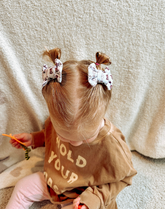 Toddler girl is wearing a pair of clip bows for little girls from By Bella Boutique.
